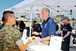 Operation Homefront CEO and President John Pray serves hamburgers to Marines at Carnival Cruise Line's First Ever Socially Powered BBQ at Marine Corps Air Station Miramar on July 5, 2017 in San Diego, California. 