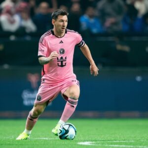 Lionel Messi, in his pink Inter Miami CF uniform, charges up the green field, the soccer ball a blur between his feet, during the Riyadh Season Cup match between Al-Hilal SFC and Inter Miami FC at Kingdom Arena on January 29, 2024 in Riyadh, Saudi Arabia. Photo by Saad Ratimi / Power Sport Images