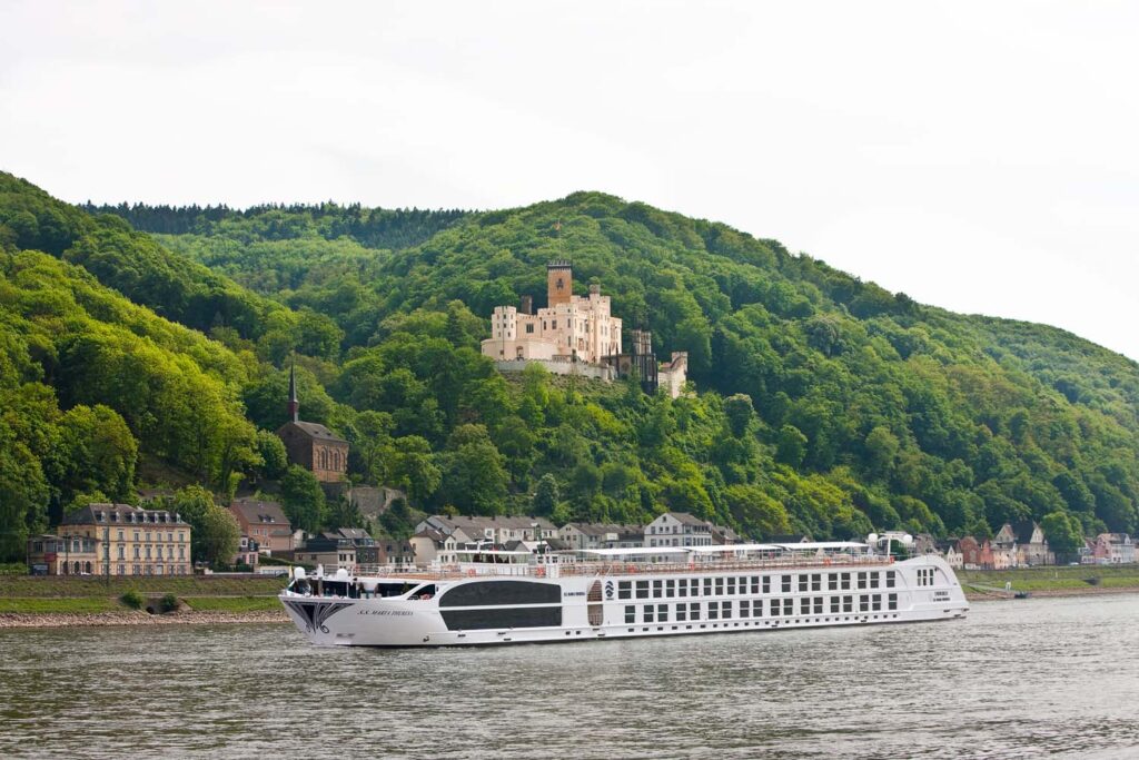 Uniworld's river ship S.S. Maria Theresa sails past a castle on the slopes of a European river bank. CREDIT: Uniworld