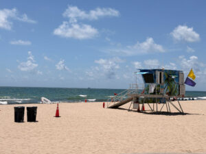 Sandy beach with waves and a large lifeguard stand.